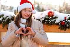 冬天肖像年轻的成人美丽的女人圣诞老人他显示心形状手指圣诞节情绪下雪冬天美时尚概念