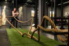 绳子仓库健身绿色男人。草培训健身房肌肉发达的年轻的强大的强度物理健康的活动人肌肉交叉地面持有