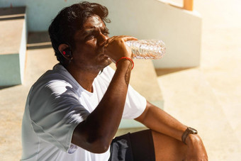 关闭亚洲年轻的体育运动跑步者黑色的男人。穿运动员耳机喝水瓶运行户外街健康公园健康的锻炼锻炼概念