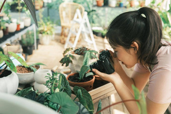 微笑年轻的女人采取智能<strong>手机图片</strong>植物小商店