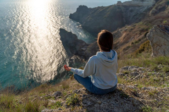 女人旅游享受日落海山景观坐在在户外岩石海穿牛仔裤蓝色的连帽衫<strong>健康</strong>的生活方式<strong>和谐</strong>冥想