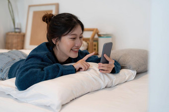 快乐亚洲女人手智能手机打字聊天谈话闲谈，聊天盒子卧室社会媒体市场概念