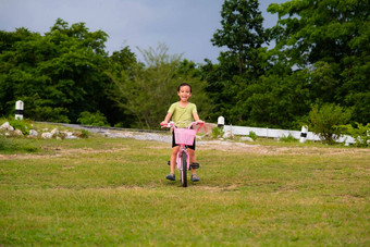 可爱的亚洲女孩骑自行车草坪上热夏天一天快乐女孩骑自行车在户外健康的夏天活动孩子们