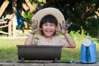 女孩穿他帮助妈妈。花园园丁可爱的女孩种植花锅可爱的女孩微笑显示脏手后院