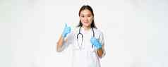 微笑亚洲女医生显示拇指穿橡胶手套诊所统一的站白色背景