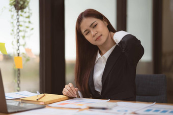 图像亚洲业务女人缓解疼痛脖子痛苦久坐不动的工作办公室并发症状概念