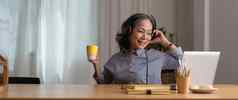 快乐高级亚洲女人穿耳机听歌曲移动PC生活房间舒适的首页