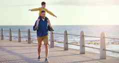 飞行高天空拍摄快乐的父亲携带儿子肩膀采取走人行道海滩