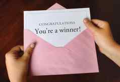 信祝贺你赢家!女手持有开放粉红色的信封