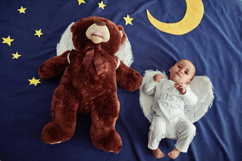 婴儿天使天堂概念拍摄可爱的婴儿男孩泰迪熊穿天使翅膀虚构的晚上时间背景