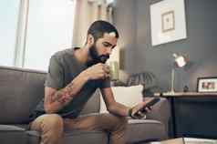 连接的事情当前的缓解技术拍摄年轻的男人。咖啡智能手机沙发首页