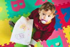 可爱的婴儿女孩假字母玩席画纸彩色的蜡笔