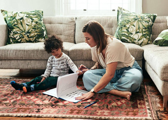 时间家庭作业拍摄快乐的年轻的女人儿子家庭作业坐着地板上生活房间
