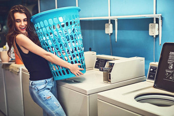 重负载拍摄有吸引力的年轻的女人持有篮子洗站内部洗衣房间一天