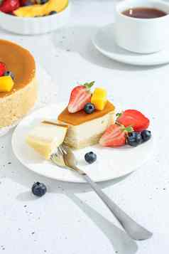 一块芝士蛋糕芒果板茶叉装饰浆果花灰色的背景健康的食物