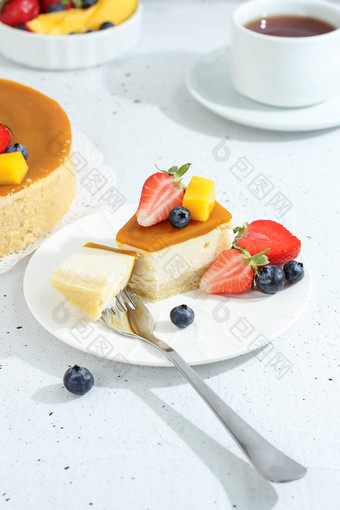 一块芝士<strong>蛋糕芒果</strong>板茶叉装饰浆果花灰色的背景健康的食物