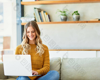 更新博客拍摄有吸引力的年轻的女人移动PC坐着沙发首页