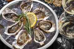 新鲜的打开牡蛎冰柠檬轮金属板香槟黑色的石头变形背景前视图特写镜头拍摄