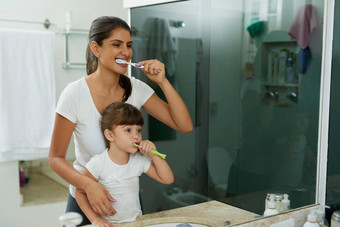 爱帮助学习健康的牙科习惯拍摄妈妈。女儿刷牙牙齿浴室首页图片