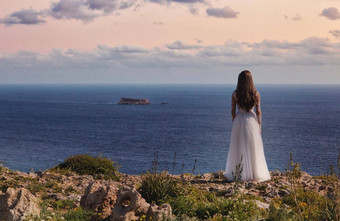 新娘白色婚礼衣服站悬崖边缘海