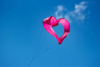 粉红色的心形的风筝飞行空气清晰的蓝色的天空背景