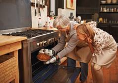 烤拍摄年轻的女人学习烘焙提示祖母