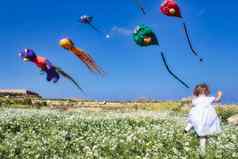 女孩运行场风筝飞行清晰的蓝色的天空