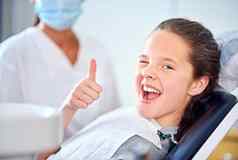 热座位肖像年轻的女孩坐着牙医椅子给拇指