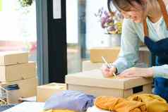 年轻的亚洲女商人开始小业务老板写作地址纸板盒子