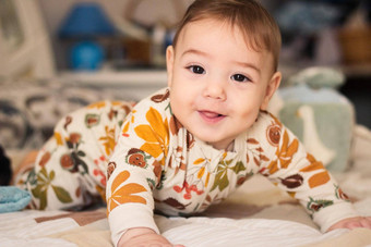 可爱的婴儿床上穿打破西装睡衣装直接相机