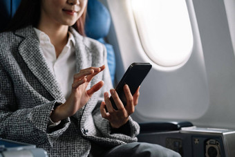 旅行技术年轻的亚洲女人飞机智能手机坐着飞机座位