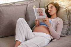 准备旅程母亲拍摄年轻的怀孕了女人阅读婴儿书首页