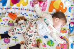 可爱的婴儿男孩睡觉色彩斑斓的床垫包围玩具