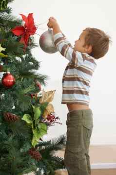 他装修树一年拍摄年轻的男孩装修圣诞节树