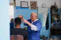 爱行工作拍摄高级男人。修剪客户头发理发师商店
