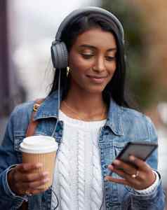 咖啡帮助保持之前拍摄年轻的女人穿耳机手机城市