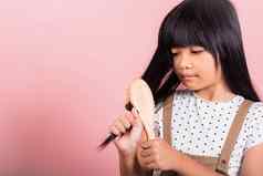 亚洲孩子年持有梳子刷牙不守规矩的触碰长黑色的头发