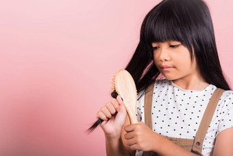 亚洲孩子年持有梳子刷牙不<strong>守规矩</strong>的触碰长黑色的头发