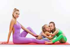 哈达瑜伽健身年轻的妈妈。教练女儿锻炼体操孤立的白色背景家庭