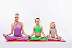 哈达瑜伽健身年轻的妈妈。教练女儿锻炼体操孤立的白色背景家庭
