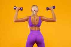 健身女人运动员健美运动员持有哑铃孤立的黄色的背景