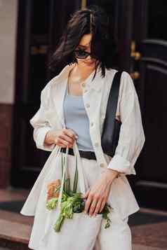 时尚的年轻的浅黑肤色的女人女人持有购物生态袋食品杂货在户外