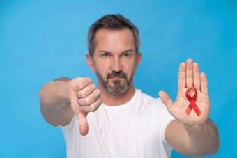 成熟的男人。手势拇指红色的丝带弓艾滋病意识象征棕榈穿白色t恤孤立的蓝色的背景现代医学医疗保健艾滋病意识概念