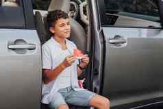 高加索人十几岁的男孩吃西瓜坐着小货车车微笑
