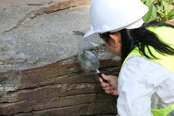 亚洲女地质学家研究员分析岩石放大玻璃自然公园探索地质学家场石头生态概念