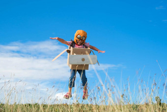 可爱的做梦的人女孩玩纸板飞机草地阳光明媚的一天快乐孩子玩纸板飞机蓝色的夏天天空背景童年梦想想象力概念