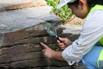 亚洲女<strong>地质</strong>学家研究员分析岩石放大玻璃自然公园探索<strong>地质</strong>学家场石头生态概念
