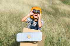 可爱的做梦的人女孩玩纸板飞机草地阳光明媚的一天快乐孩子玩纸板飞机蓝色的夏天天空背景童年梦想想象力概念