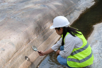 亚洲女地质学家研究员分析岩石放大玻璃自然公园探索地质学家场石头生态概念