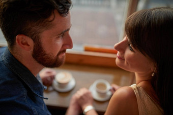他们时刻拍摄充满深情的年轻的夫妇深情地别人眼睛坐着咖啡商店日期